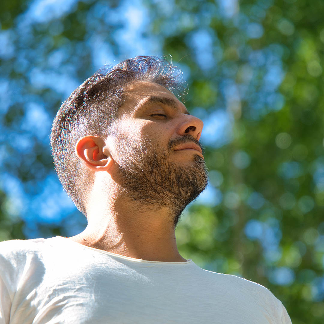 A man outside relaxing with his eyes closed.